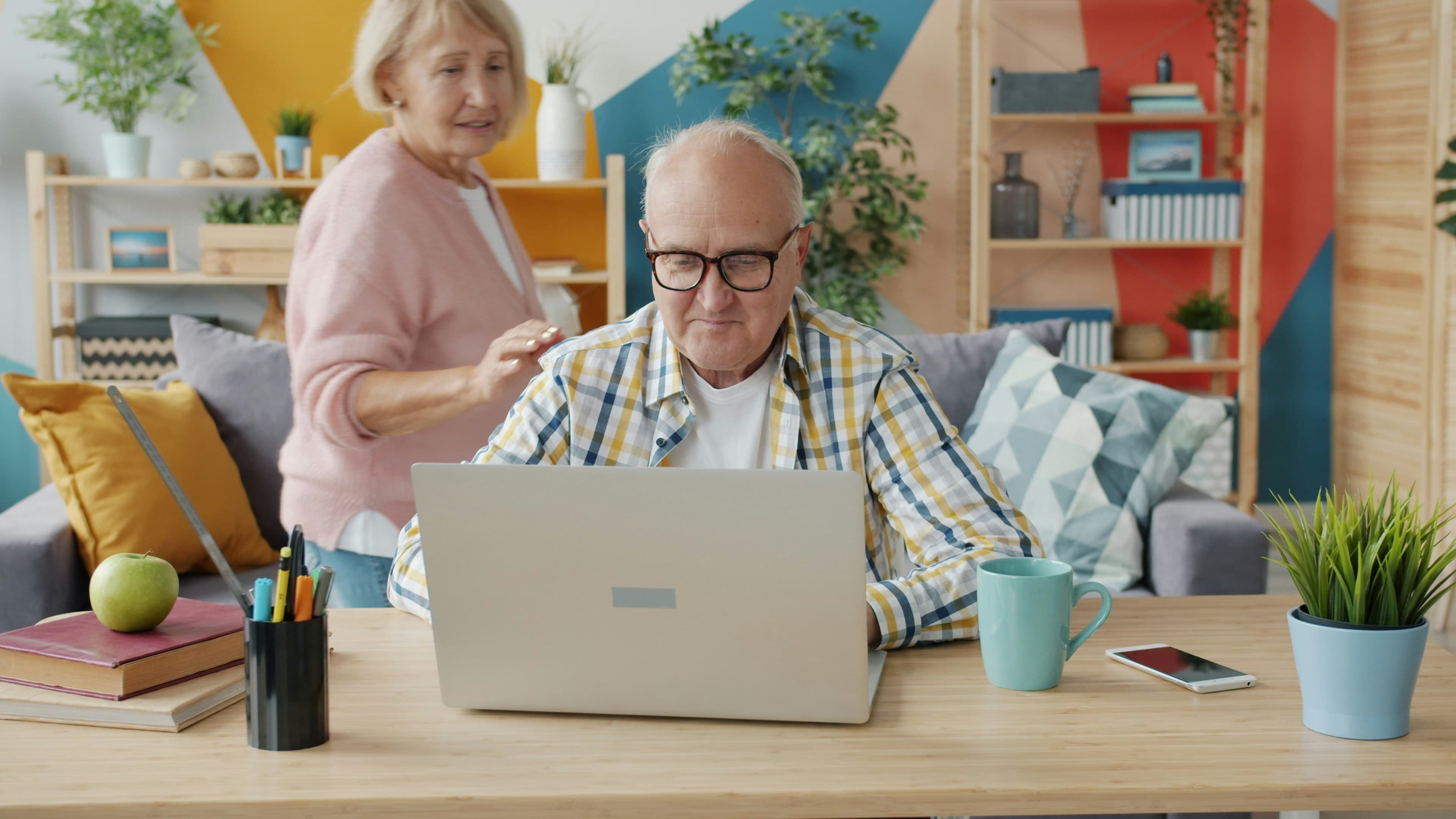 Ældre par sidder sammen i stuen og kigger på en bærbar computer
